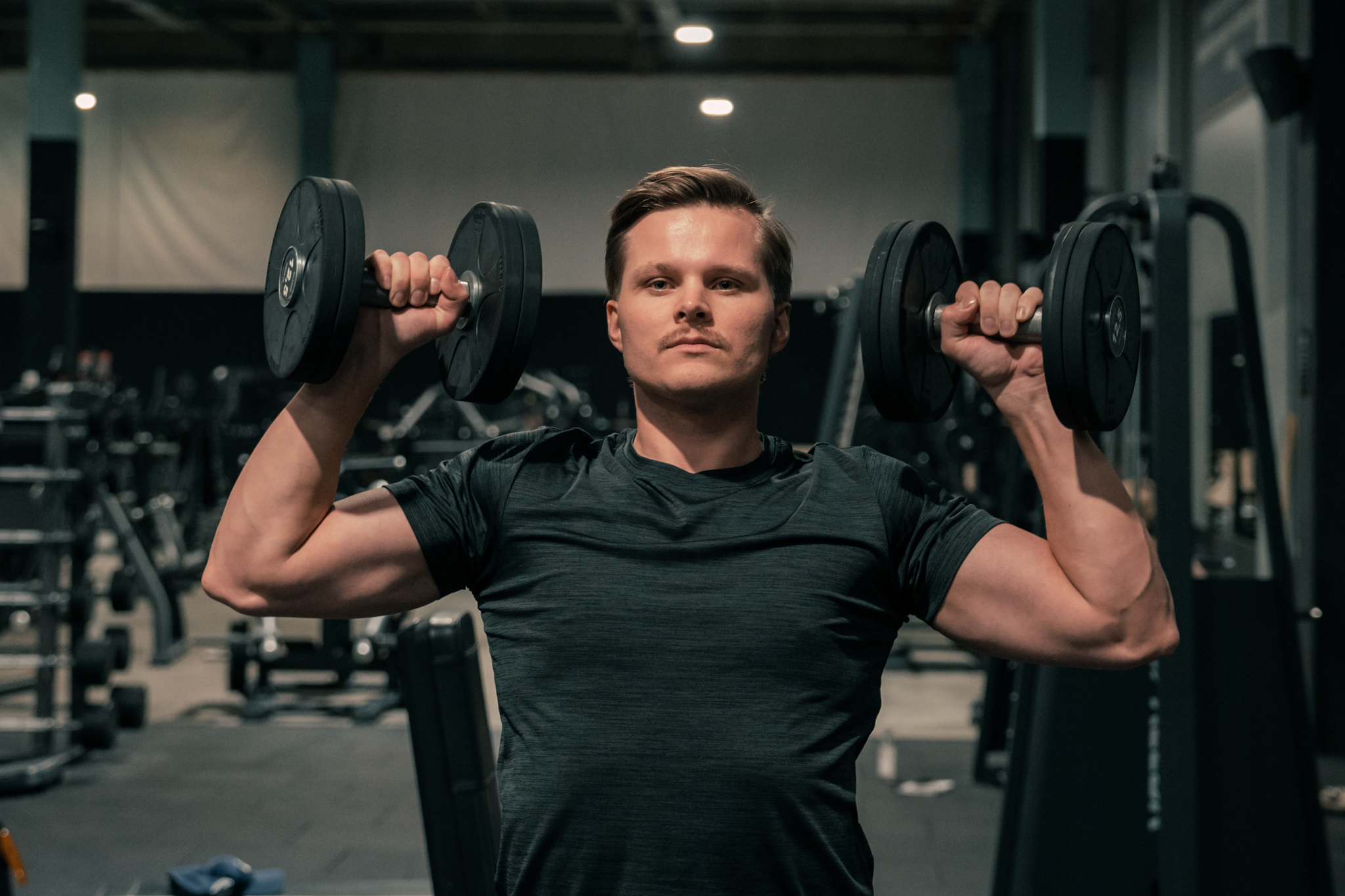 A person performing a dumbbell shoulder press at the gym