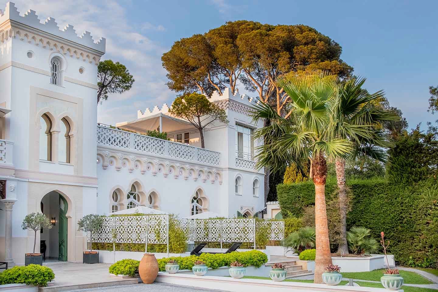 La Villa Mauresque vue de l'extérieur. Façade blanche et palmiers.