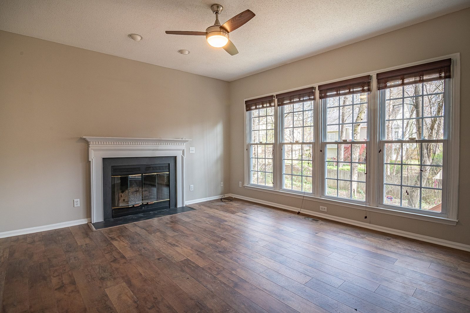 Empty living room with a fireplace and hardwood floors, photographed for a real estate listing before virtual staging