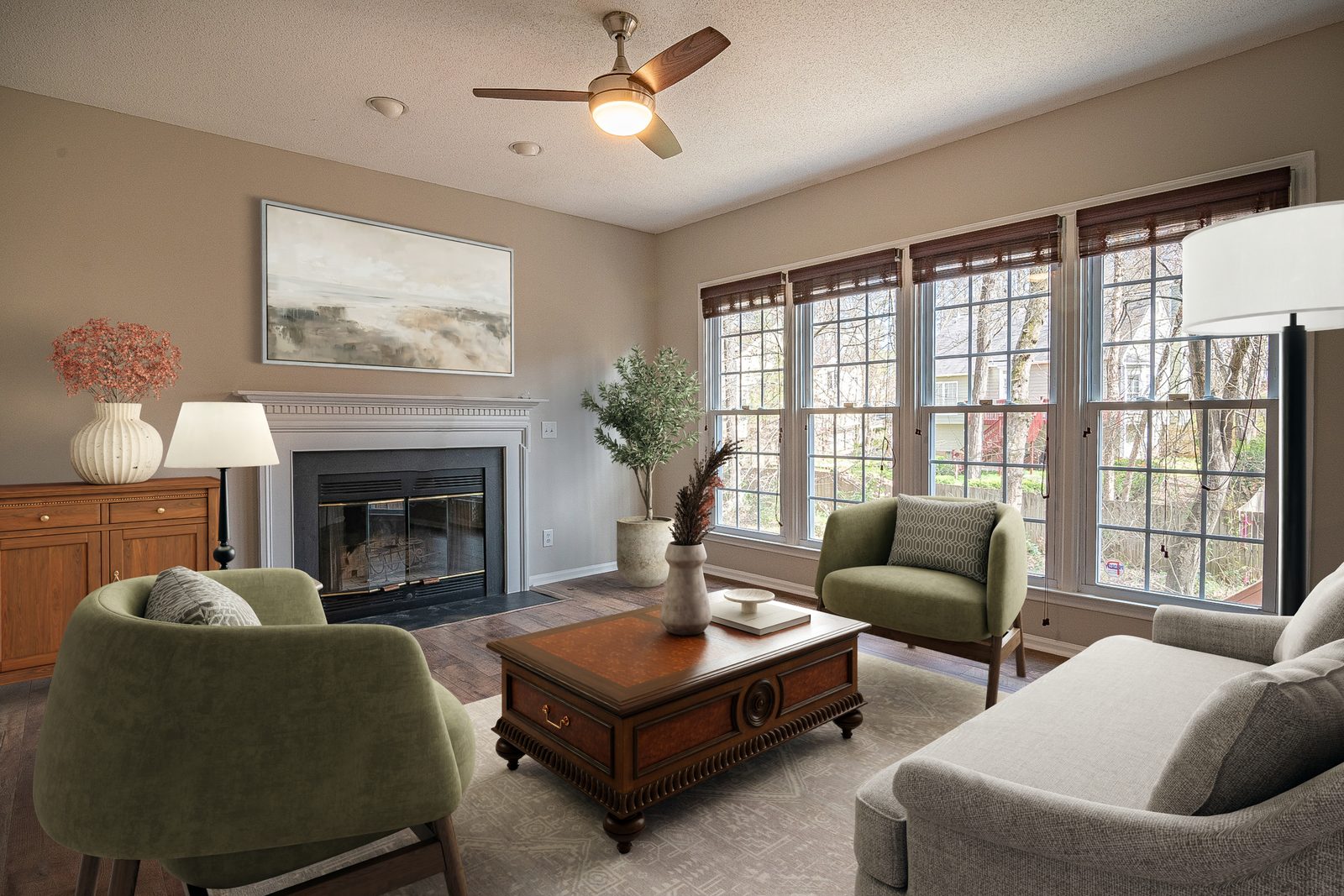 The same living room virtually staged by Apply Design with green armchairs, a wooden coffee table, a sofa and framed art above the fireplace