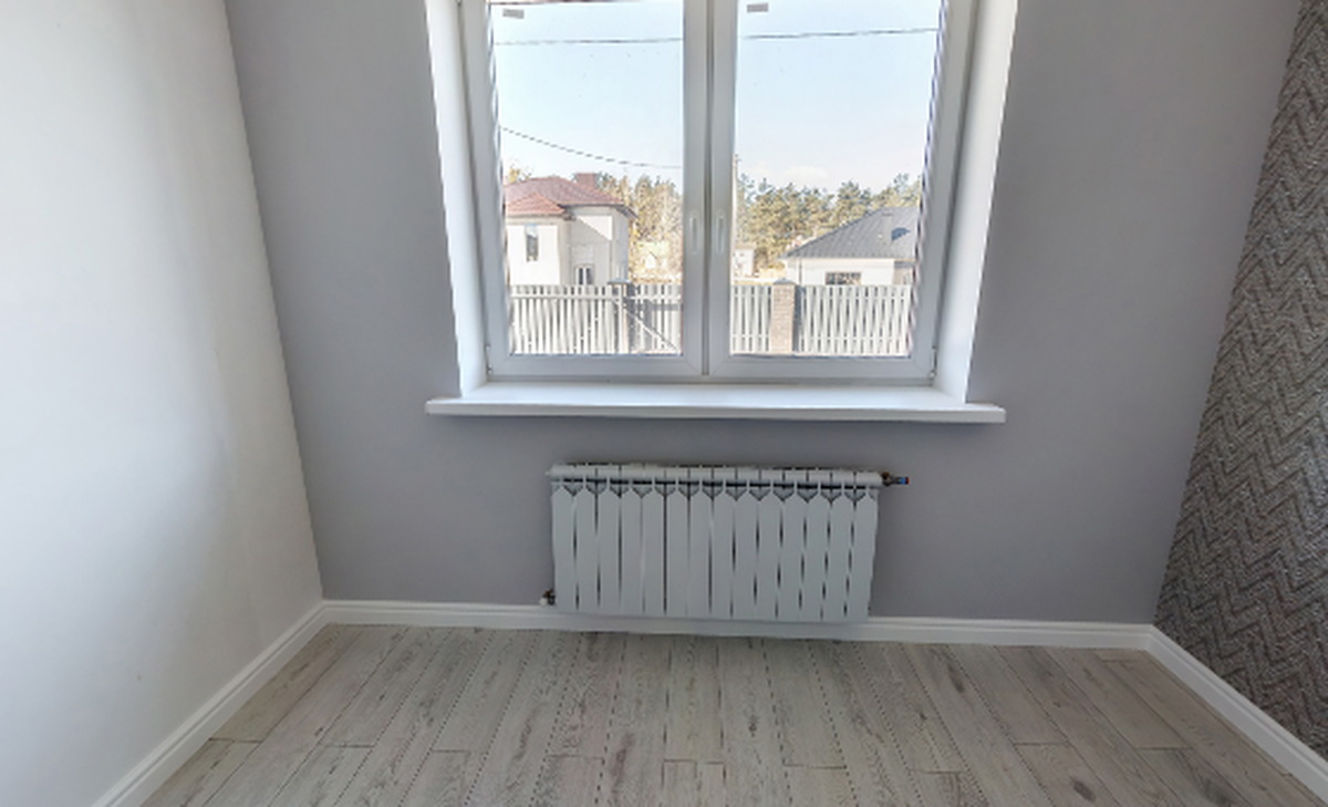 View inside an empty bedroom taken from a 360 degree panorama, showing patterned wallpaper, a window and bare flooring