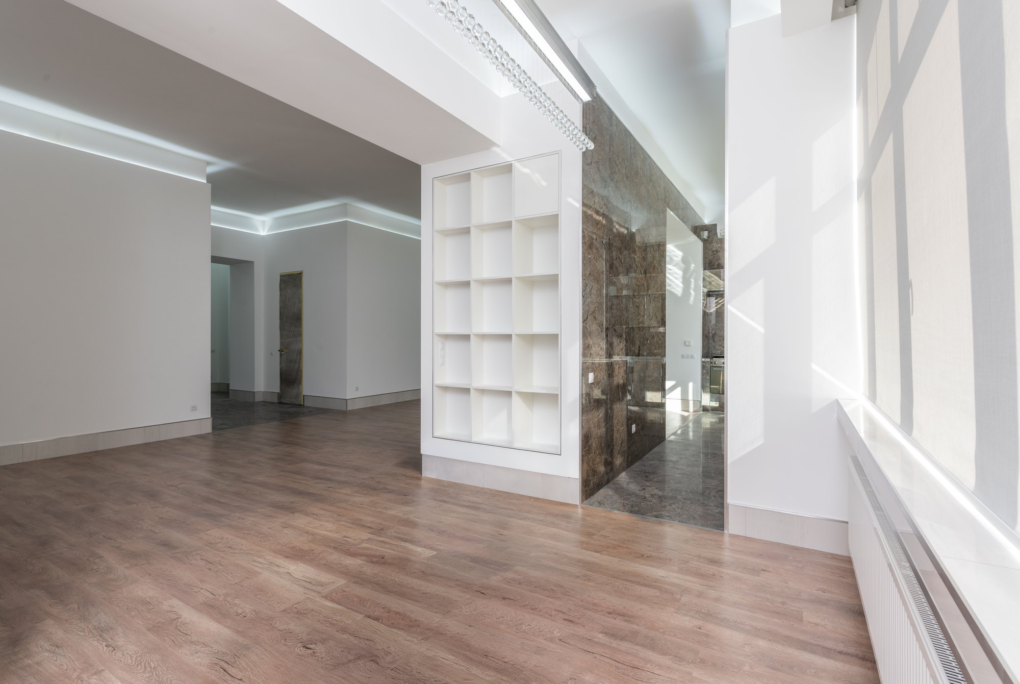 The same dining area empty, showing bare floorboards, the built-in shelving unit and the marble wall
