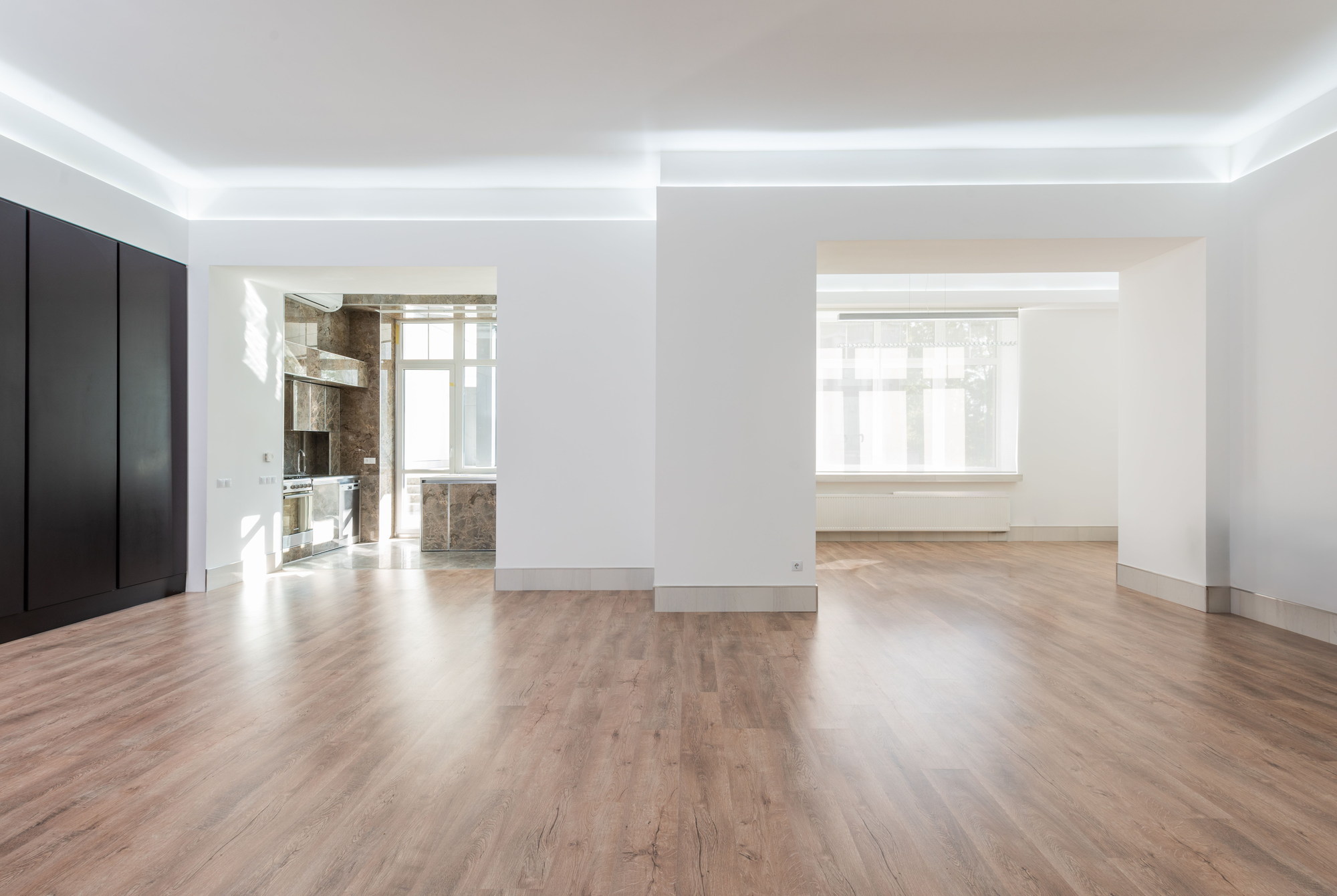 The same second angle empty, showing the dark panelled wall, bare floor and the doorway through to the kitchen