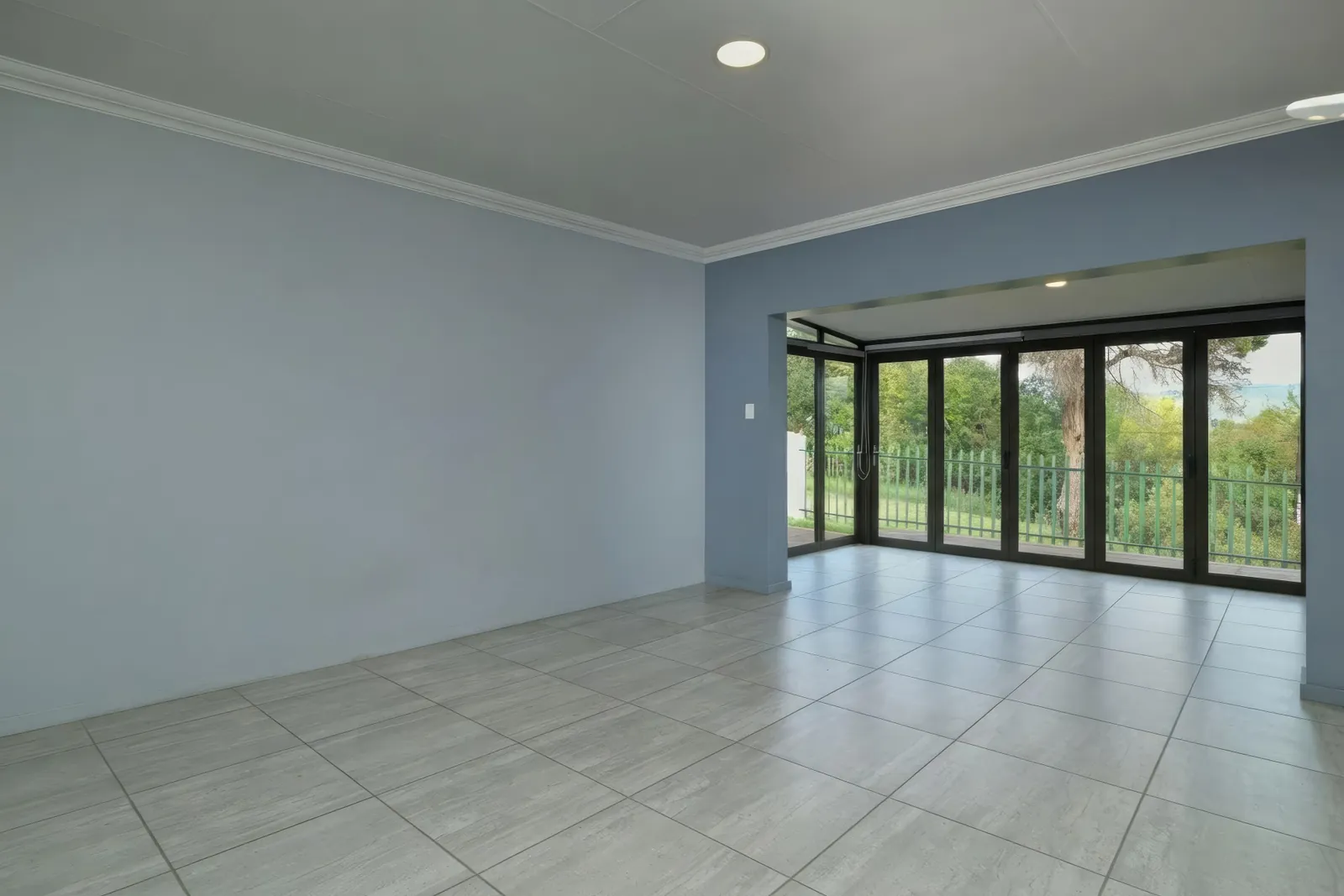 The same living room after AI furniture removal, empty with a clean tile floor