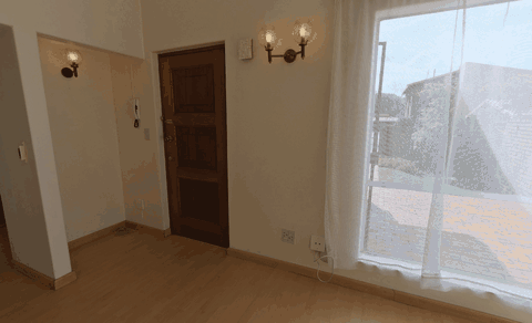 The same turn around the living room before staging, showing bare floors, the curtained window, the front door and the hallway