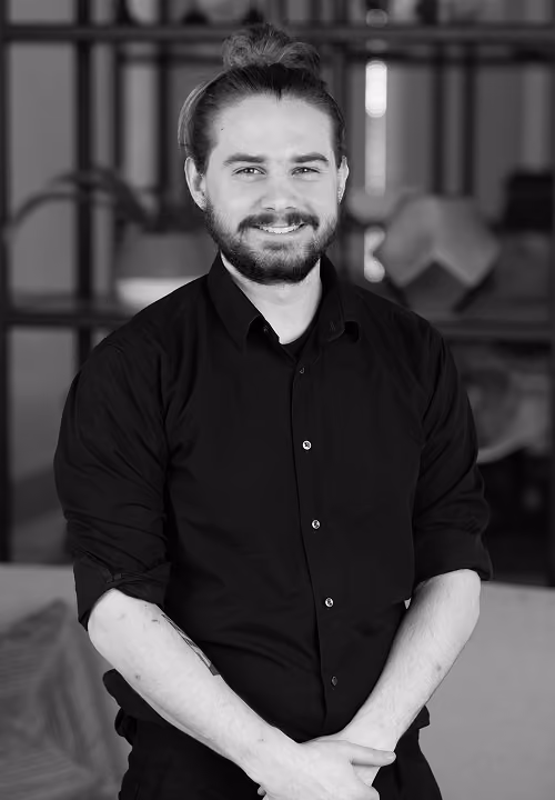 Smiling man with shoulder-length hair and beard wearing a Modern Practice long-sleeve shirt indoors.