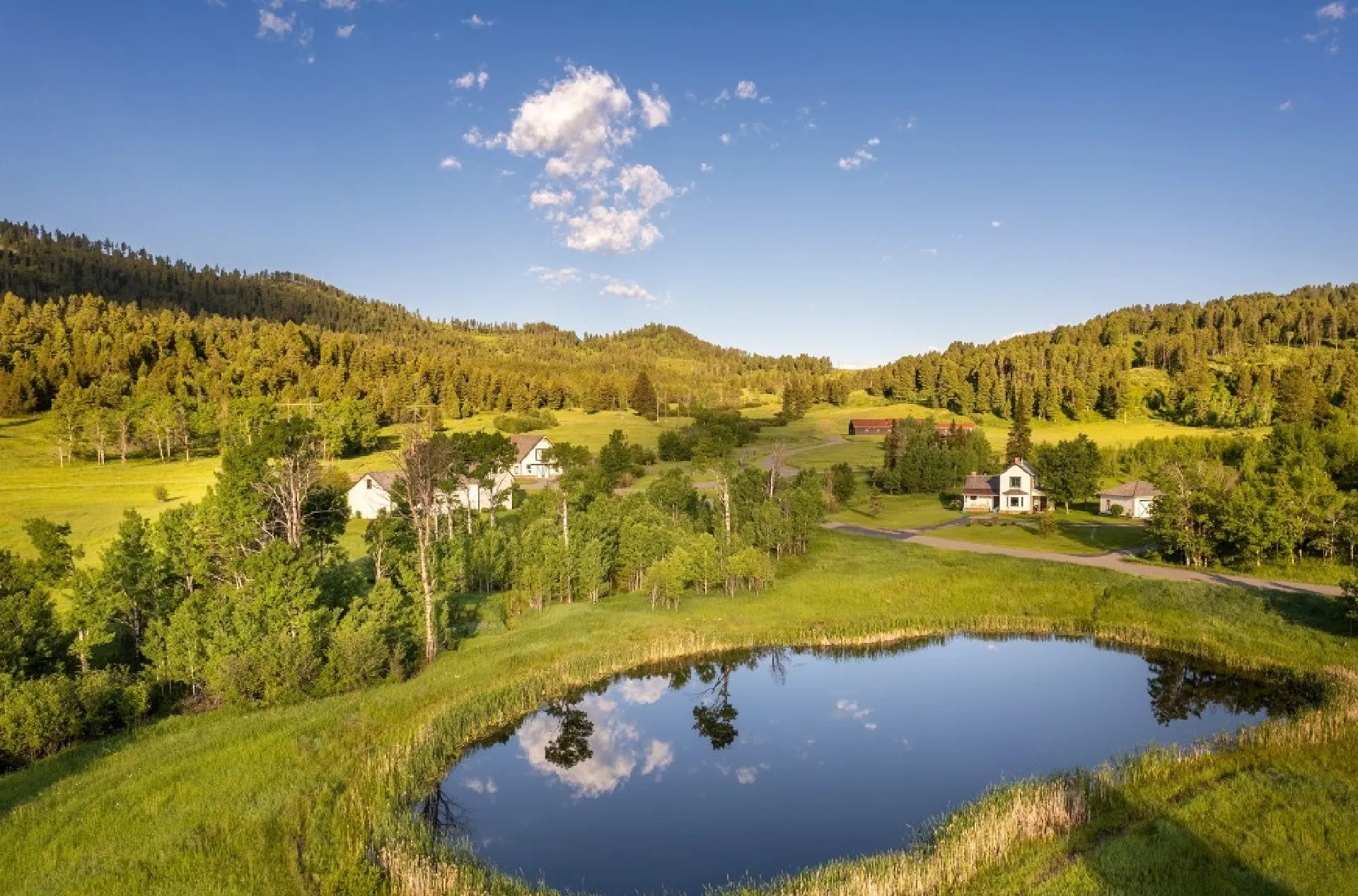Homes beside a pond in a forested Montana valley