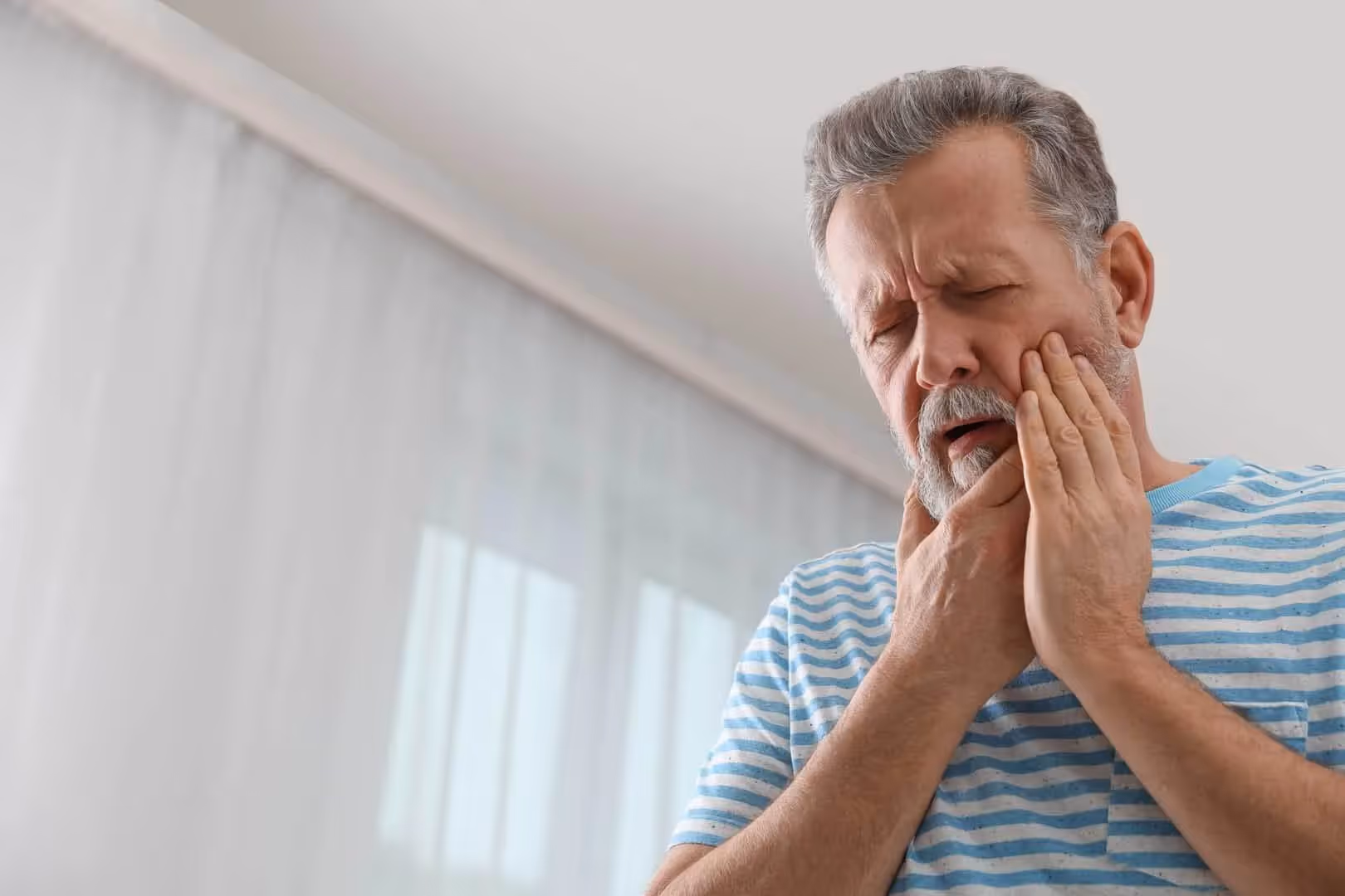 Man holding his jaw in pain from a cracked tooth