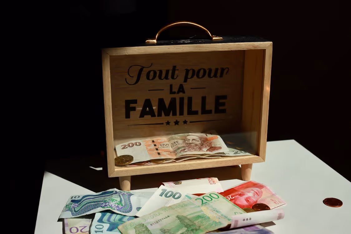 Free A wooden box with money and 'Tout pour la Famille' text, symbolizing family savings. Stock Photo