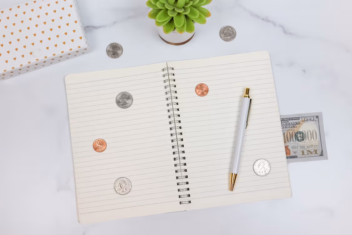 Free An organized workspace with a notebook, pen, and currency on a marble desk, ideal for finance planning. Stock Photo