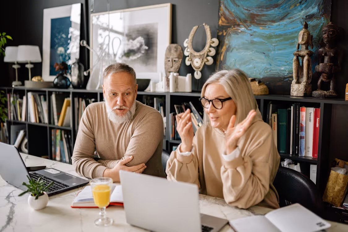 Free Senior couple enjoys online learning in a cozy home setting with laptops and books. Stock Photo