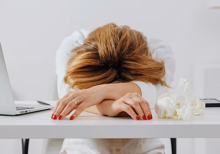 A woman sitting at a desk with her head in her arms
