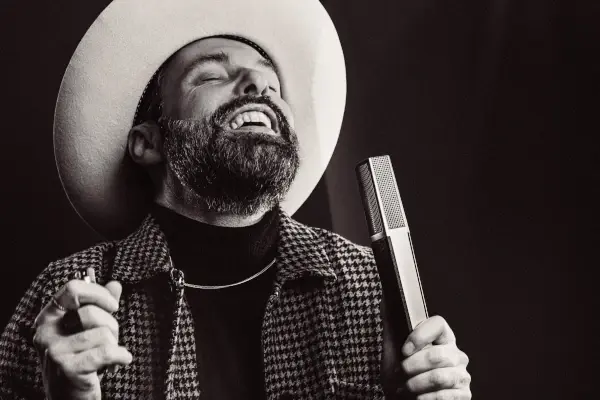 San2 beim Singen im Studio – charismatischer Rhythm & Blues Künstler mit markantem Stil und Vintage-Mikrofon.