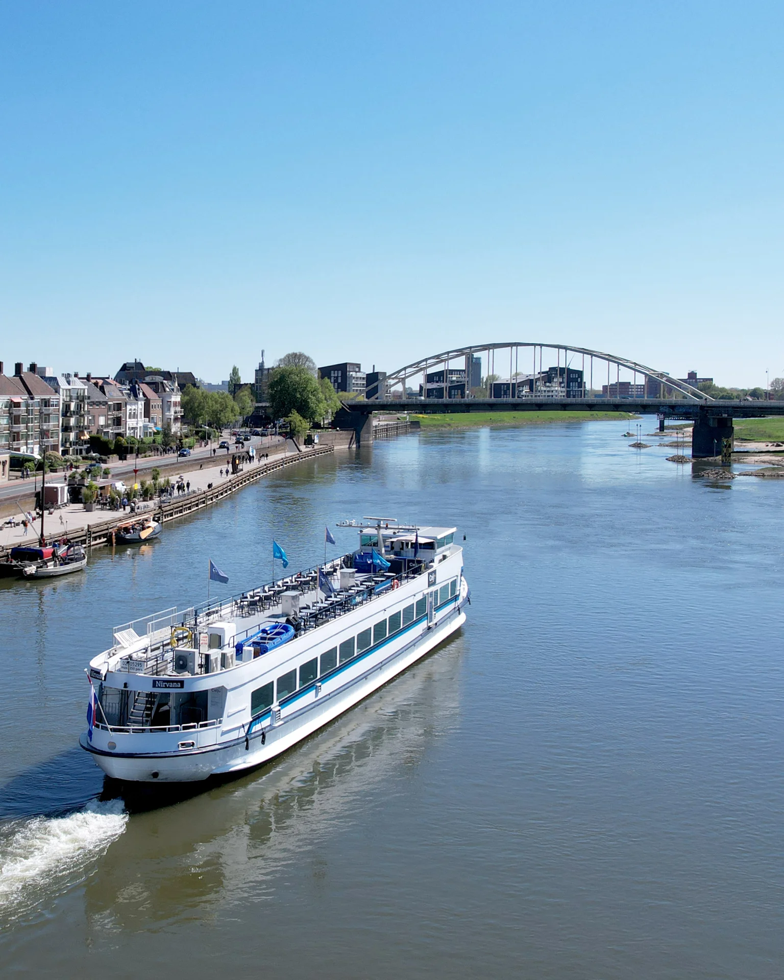 Partyschip de Nirvana, liggend aan de kade in Deventer (gemeente Salland) aan de rivier de IJssel in provincie Overijssel. Met blik op de Lebuïnuskerk en de Wilhelminabrug. Fotograaf: Edwin Mooijaart.