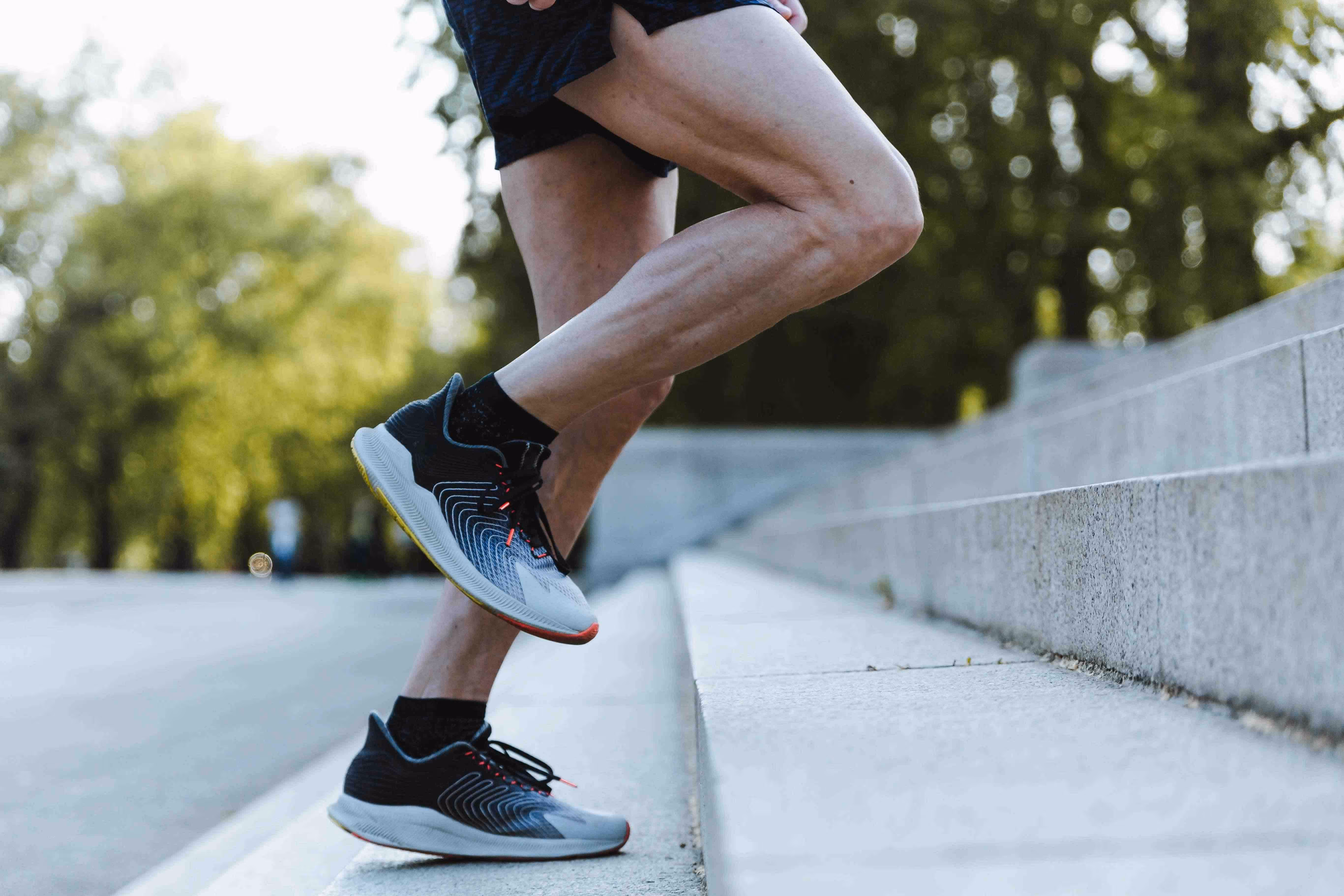 Person mit kurzer Sporthose und Laufschuhen joggt eine breite Treppe hoch