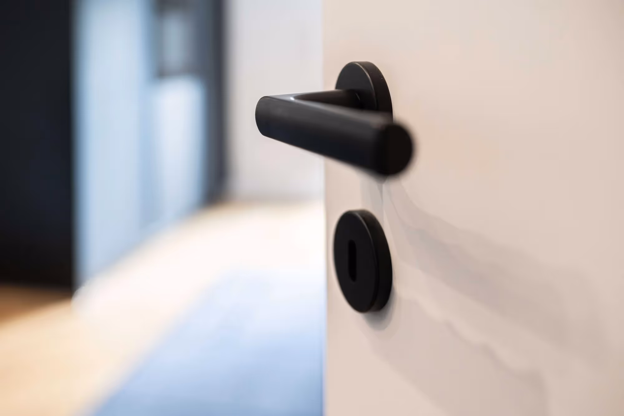 Nahaufnahme eines modernen schwarzen Türgriffs an einer weißen Tür.