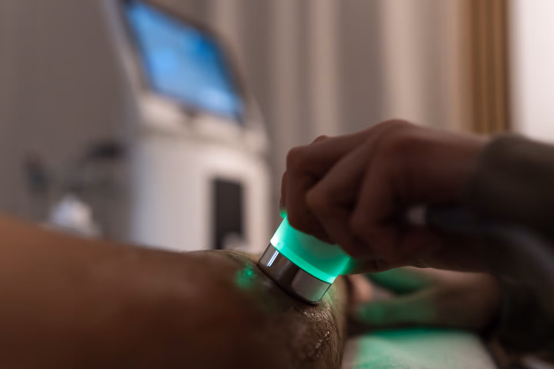 Ultraschall-Behandlung am Unterarm eines Patienten im abgedunkelten Therapieraum.