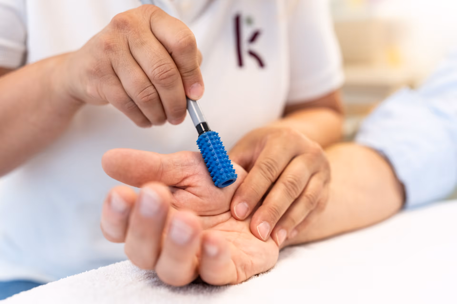 Therapeutin stimuliert die Hand eines Patienten mit einem Derma-Roller.