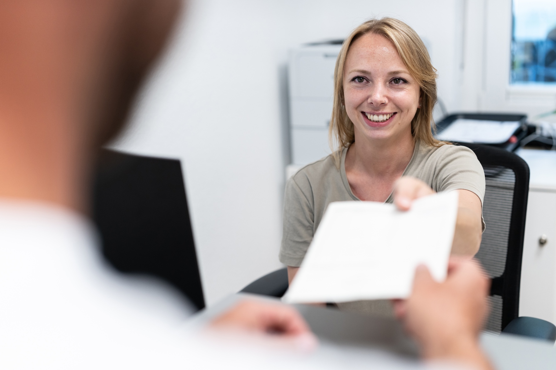 Interaktion zwischen einer Verwaltungsangestellten und einem Patienten an der Anmeldung der Praxis