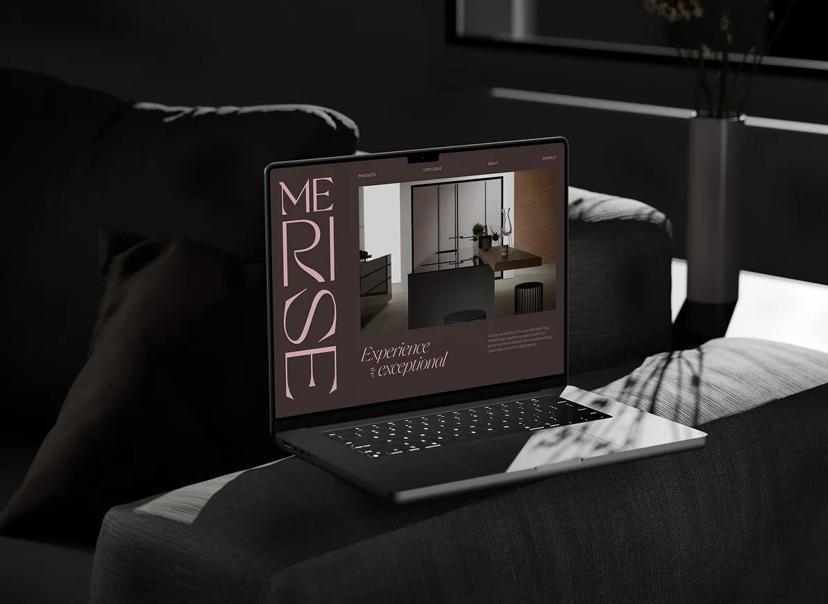 Laptop on a dark gray couch displaying a website with the text 'MERISE' and 'Experience exceptional' alongside an image of a modern interior.