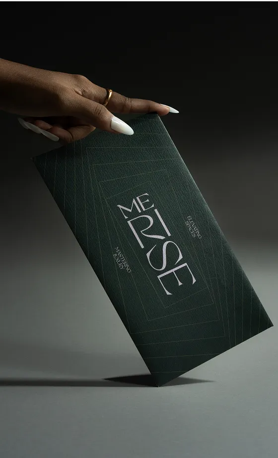 Hand with white nail polish and a gold ring holding a dark green envelope labeled MERRISE.