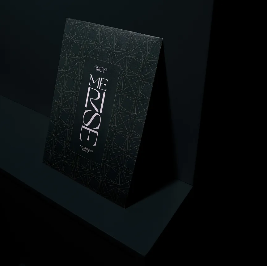 Black brochure with geometric line patterns and vertical text 'MERISE' placed on a dark surface.