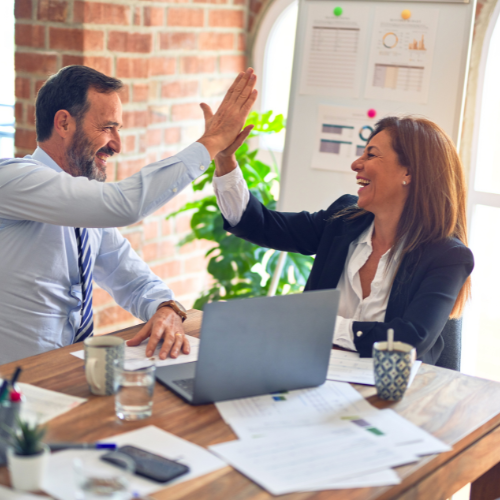 A CEO and a business partner doing a high five and smiling
