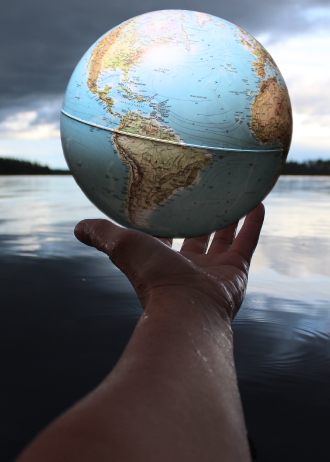 A globe in a hand with a sea background