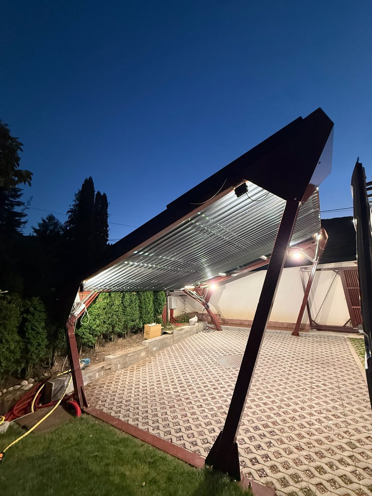 Solar carport lit from below in the evening, with solar panels forming the roof surface