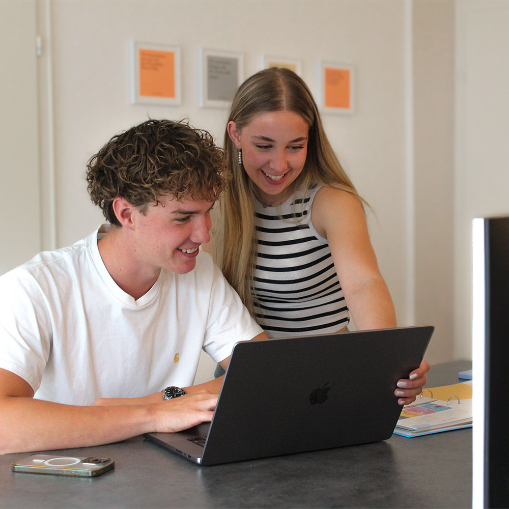 Bürosituationen zwischen zwei Mitarbeitenden am Laptop