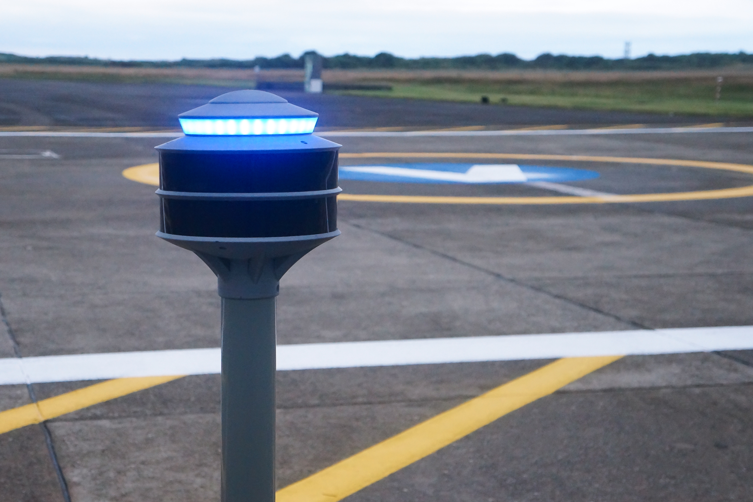 A photo of SLiNK-TECH's PORTAL device, shown on the edge of a drone vertiport in an airfield.