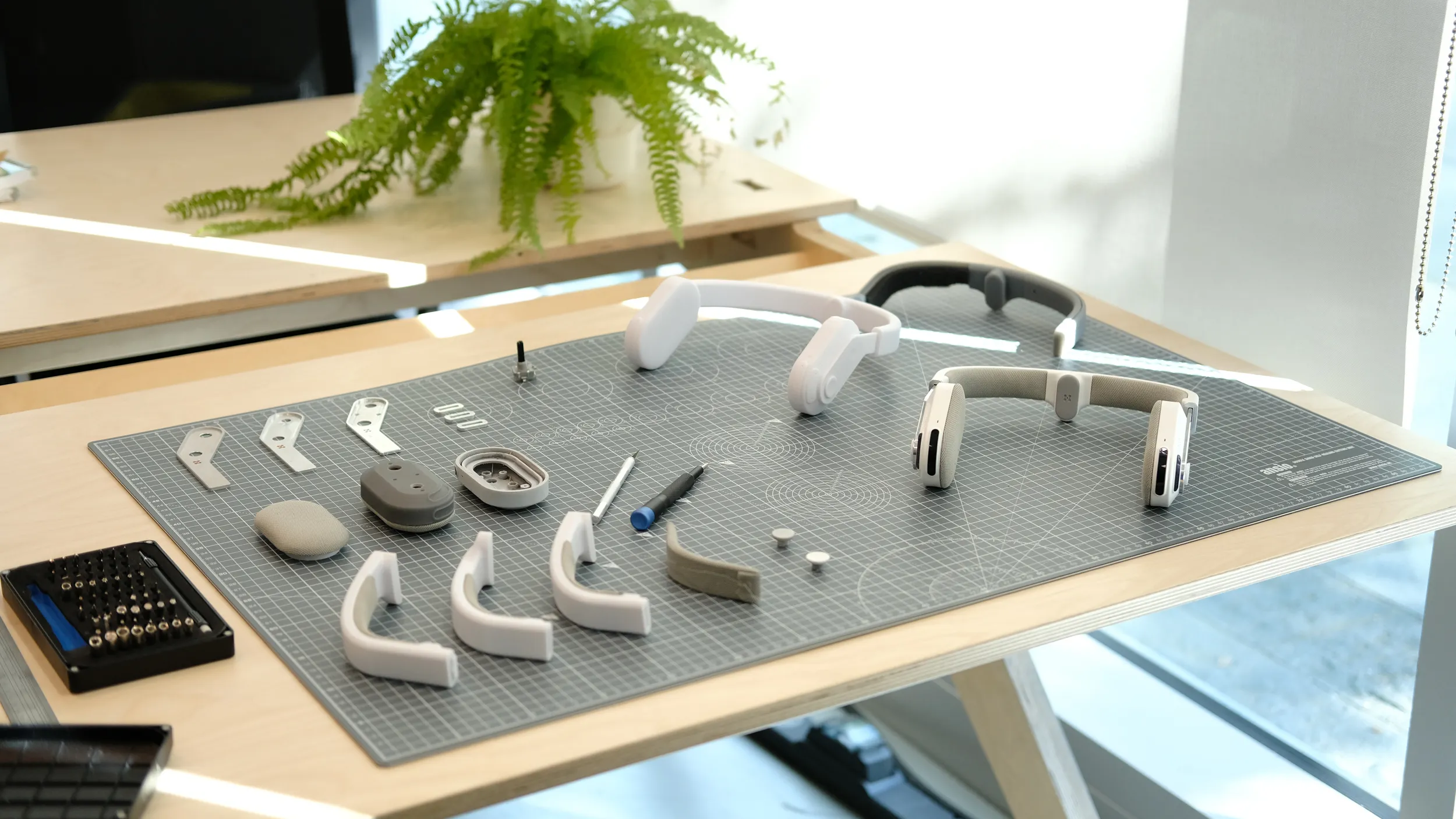 A visual model of the Sixth Sense product, shown alongside earlier prototypes and tools, on a grey cutting mat.
