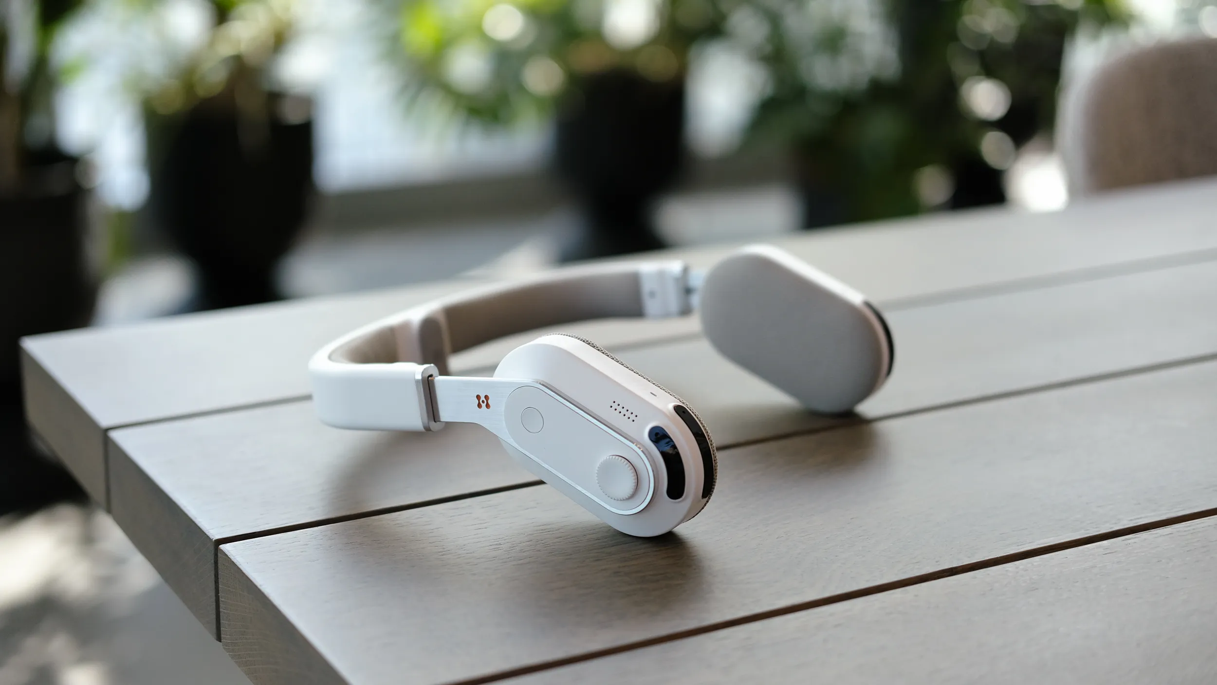 The Sixth Sense assistive wearable product for visually impaired people, placed on a brown wooden table with blurred foliage in the background.