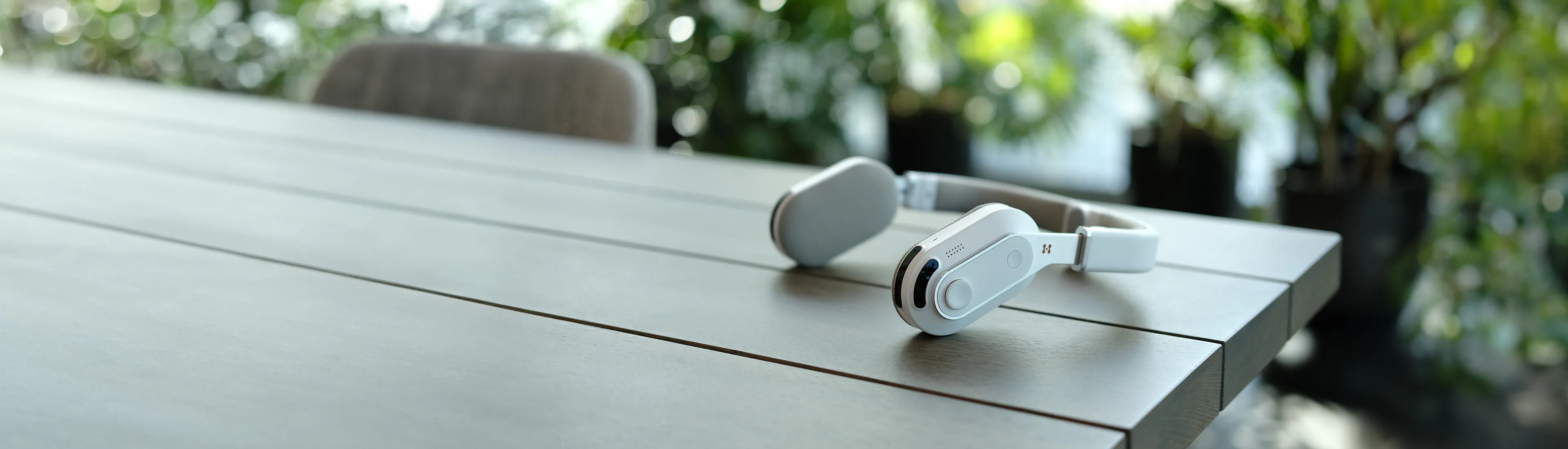 Sixth Sense wearable navigation aid by Hope Tech, resting on a wooden table with blurred greenery in the background.