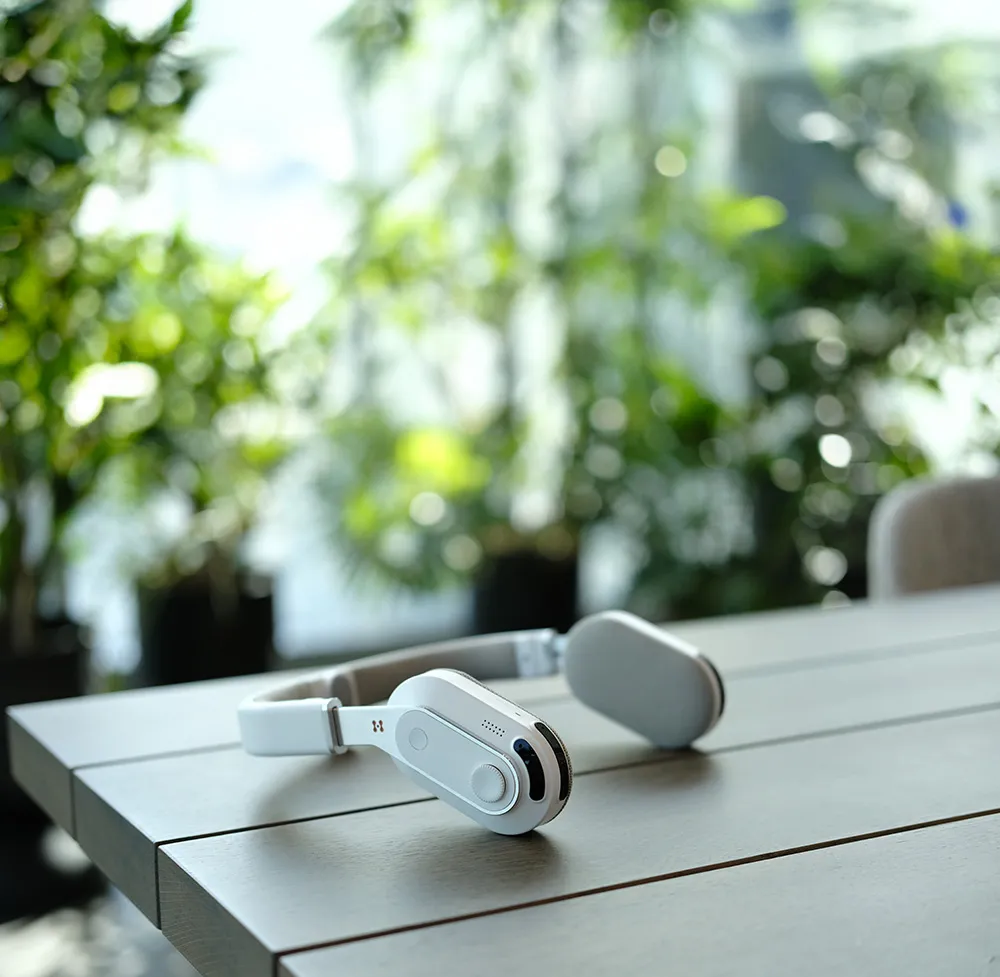 Sixth Sense wearable navigation aid by Hope Tech, resting on a wooden table with blurred greenery in the background.