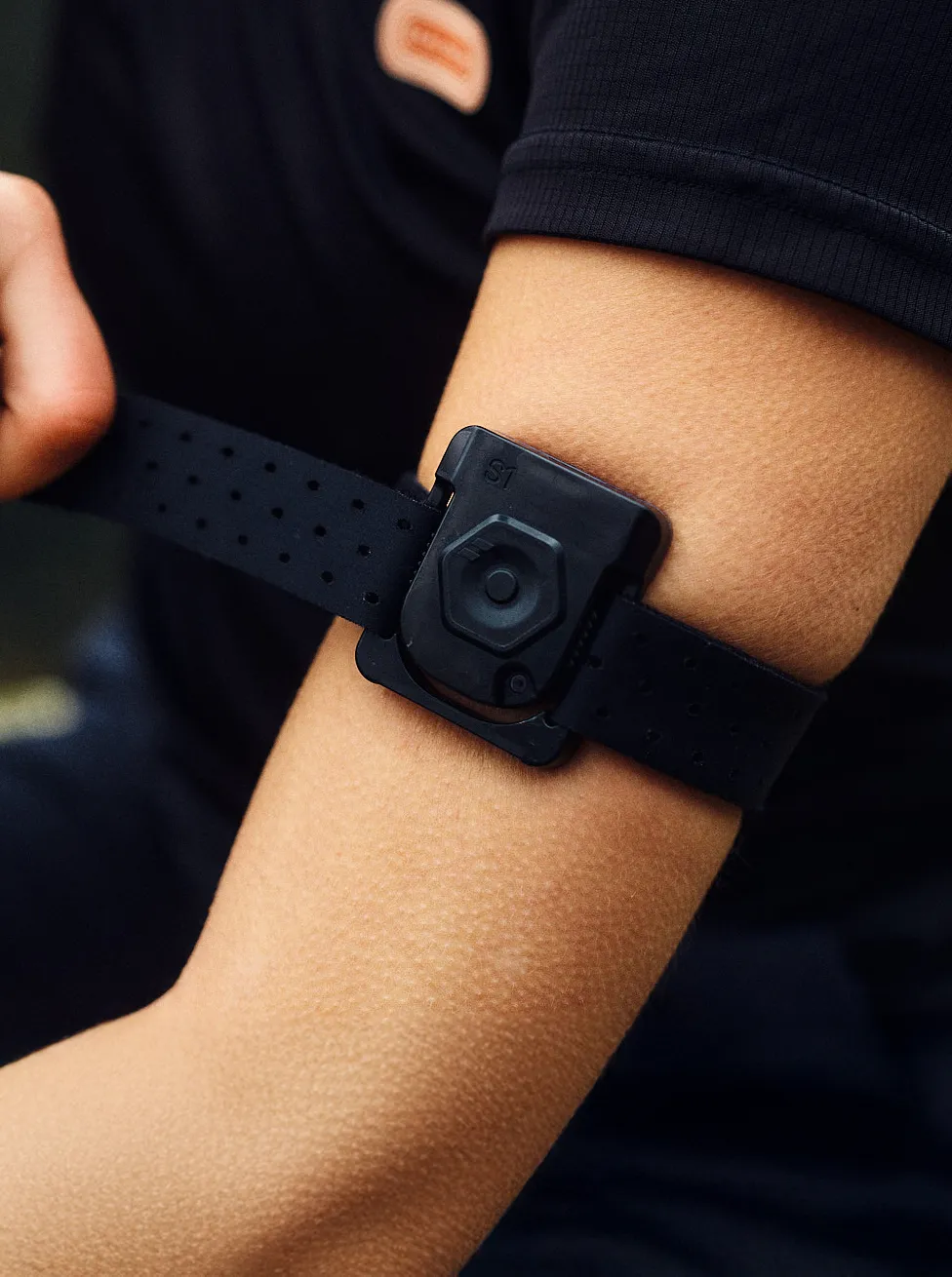 Person tightening a FLOWBIO smart hydration sensor onto their upper arm.