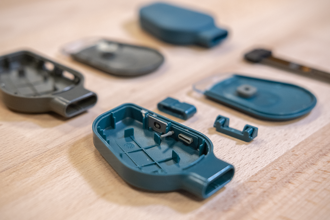 Various injection-moulded plastic components of a disassembled SmartyPlants device arranged on a desk.