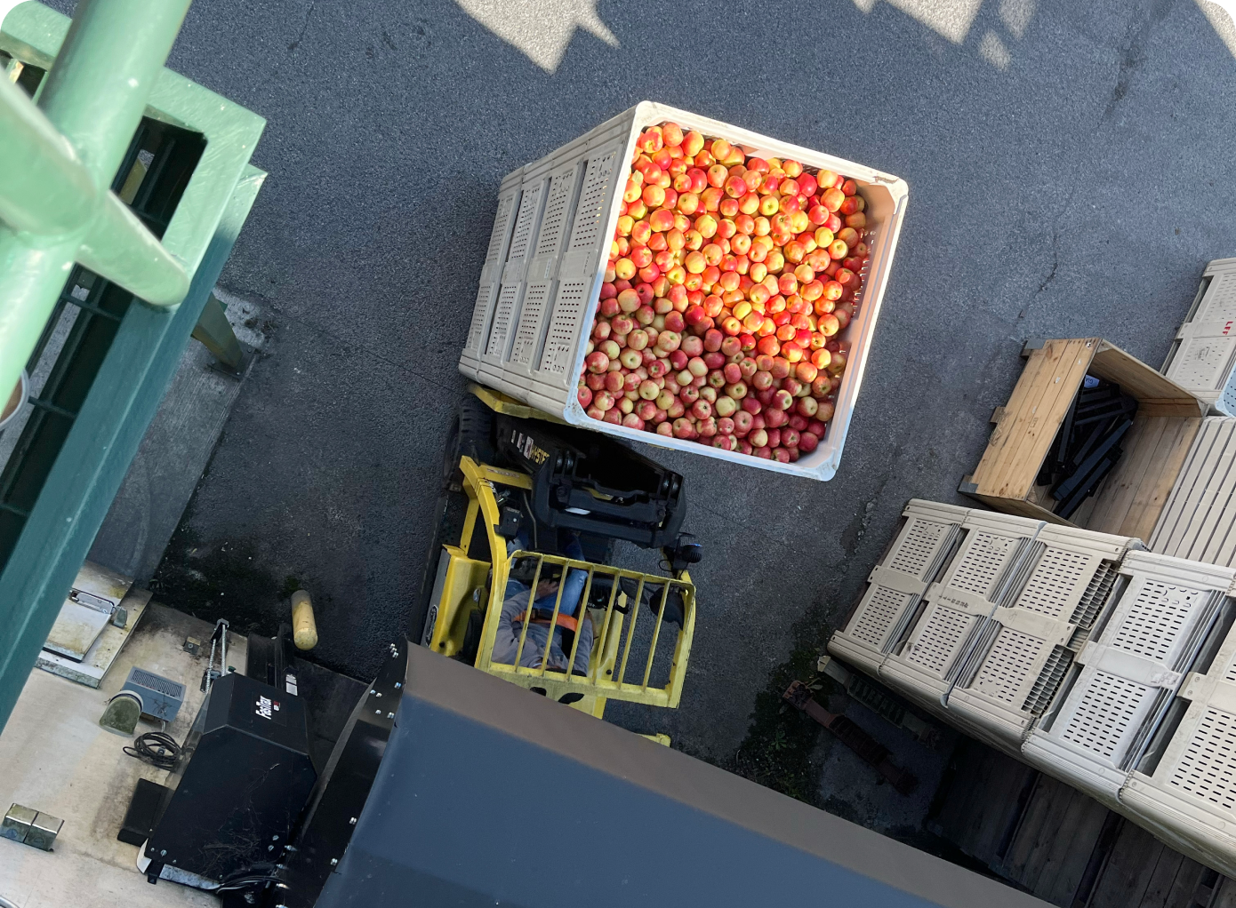 An aerial shot of a worker operating a forklift to move many boxes of apples