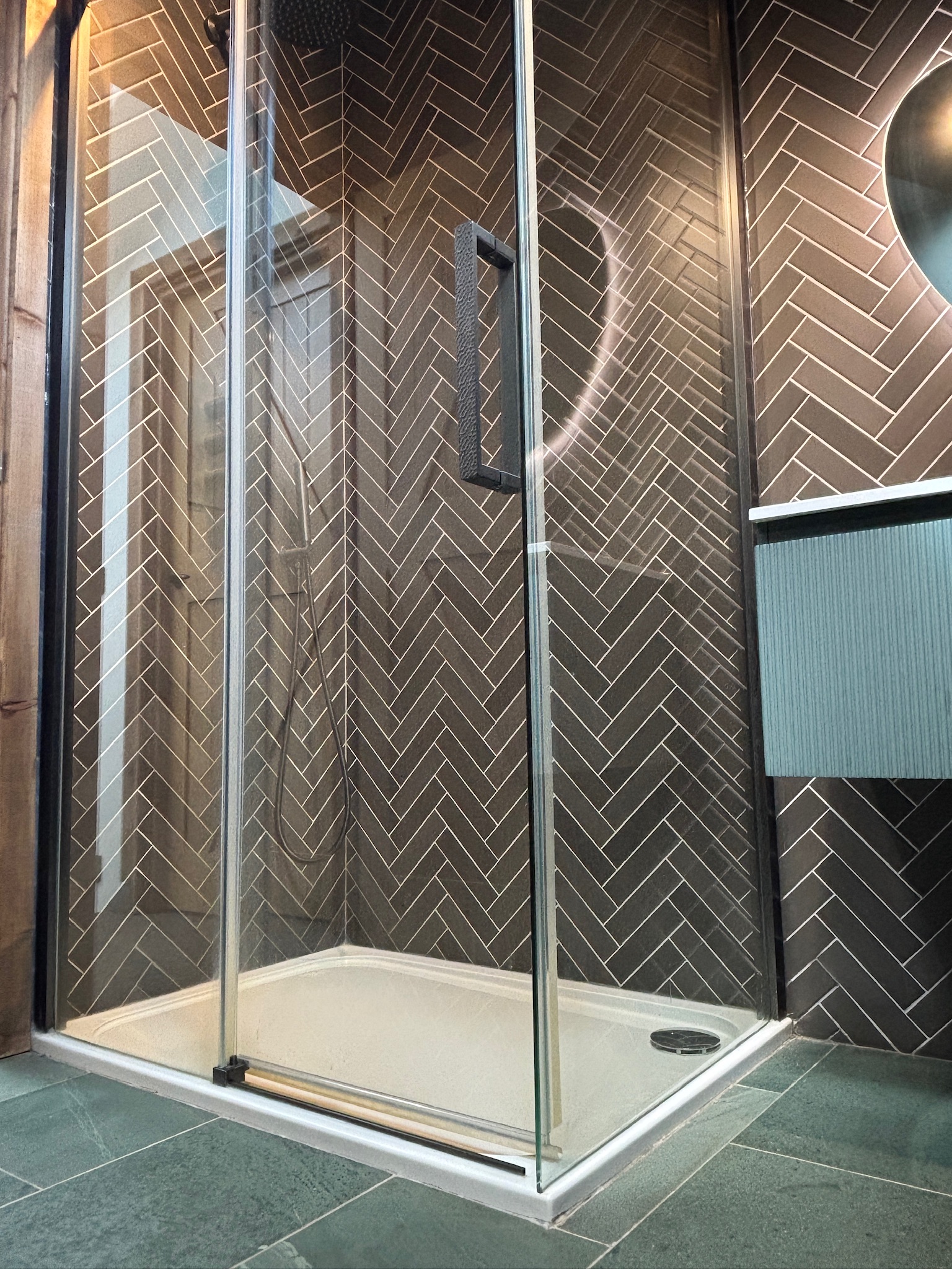 Lake District slate flooring with herringbone wall tiles in modern ensuite bathroom.