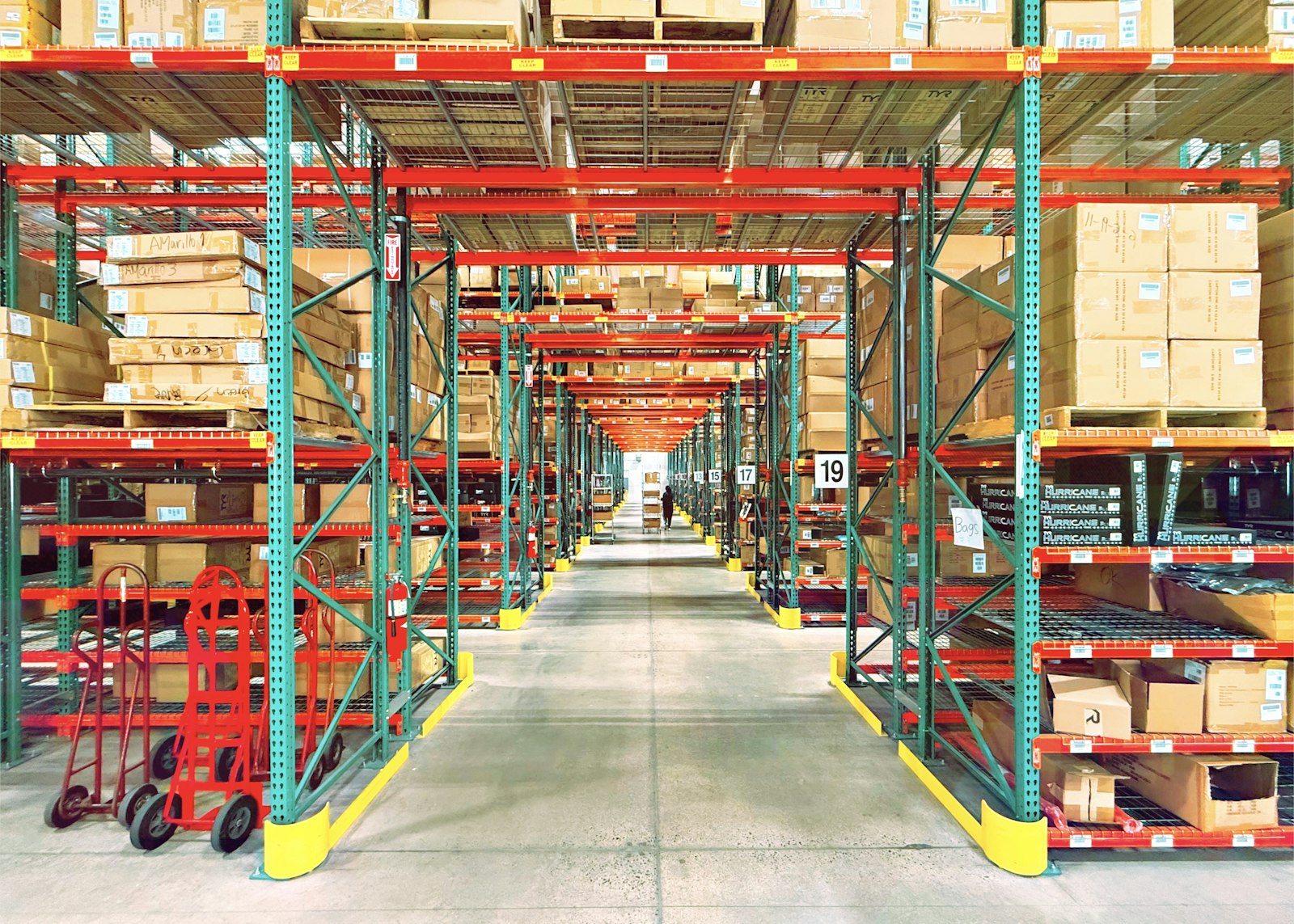 Warehouse aisle with tall racking and a worker in the distance