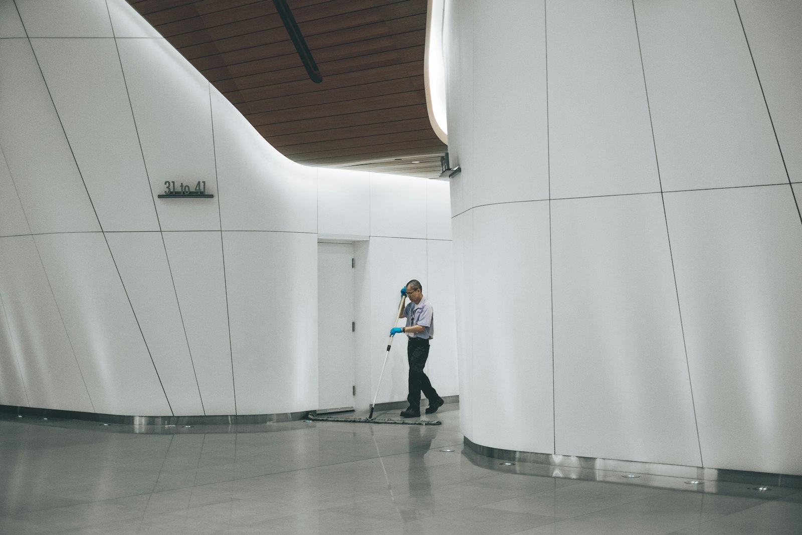 Janitor mopping the floor of a bright commercial building corridor