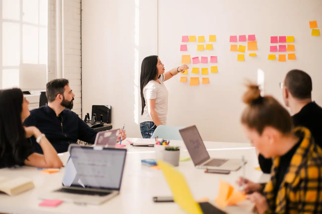 A woman is training her team using a whiteboard and visuals