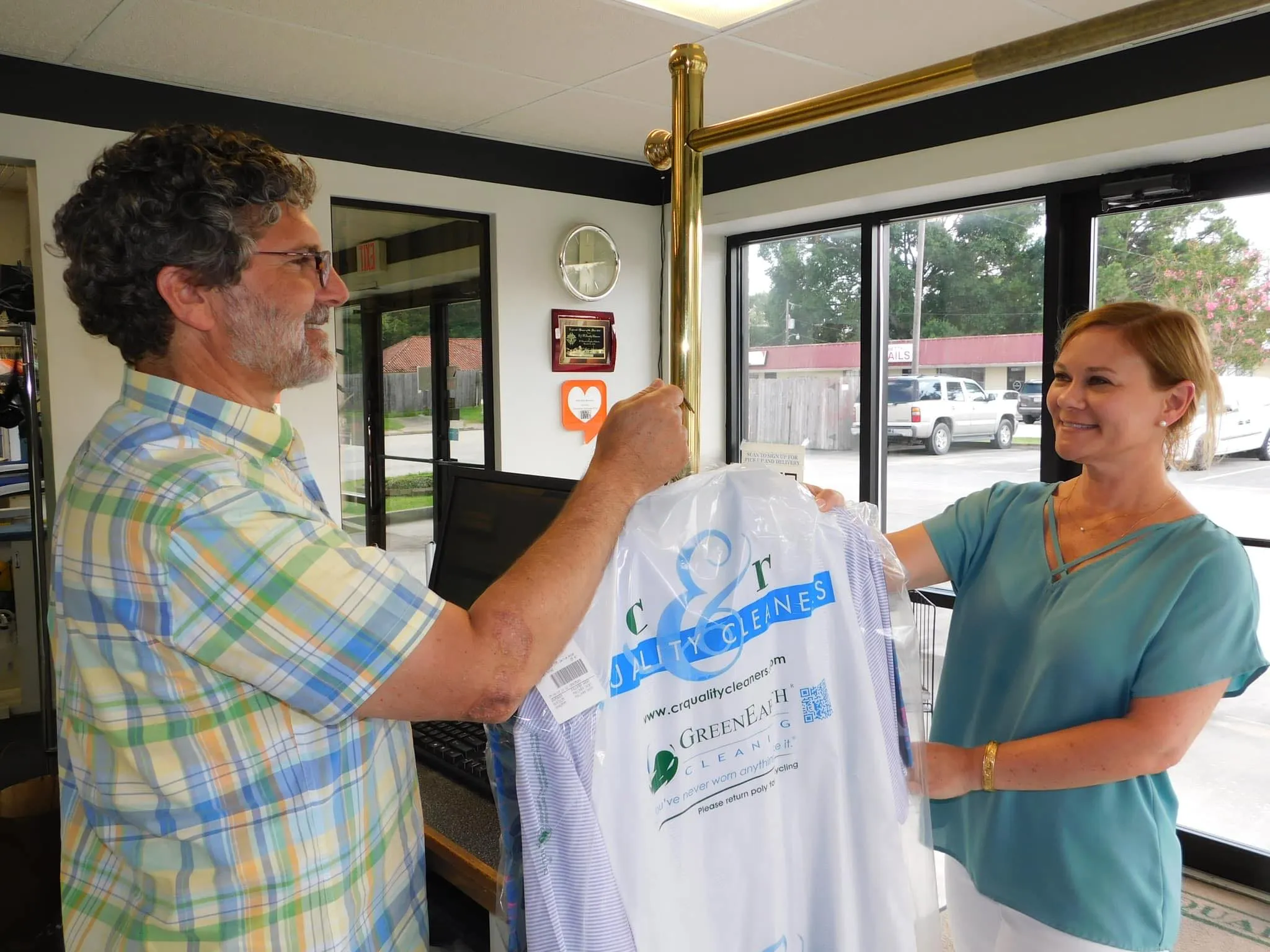 A woman being handed her dry cleaning from C&R Cleaners