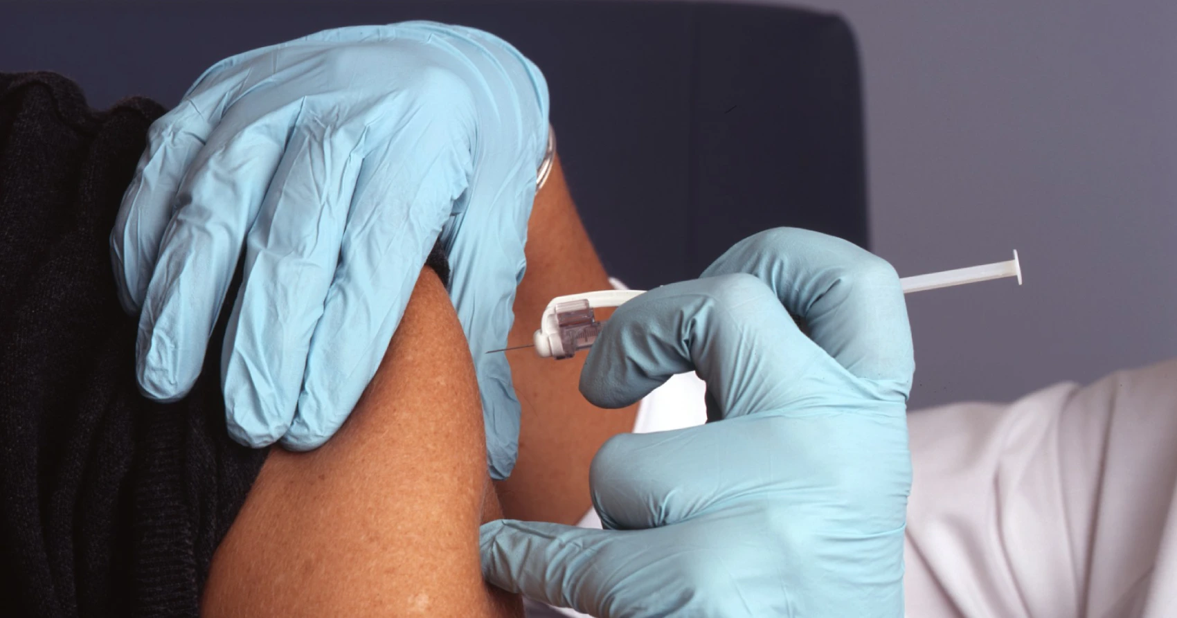 Enfermeira aplicando vacina no braço de paciente