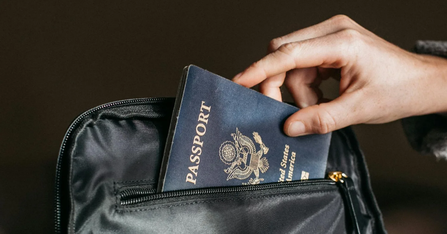 Pessoa pegando um passaporte em uma bolsa