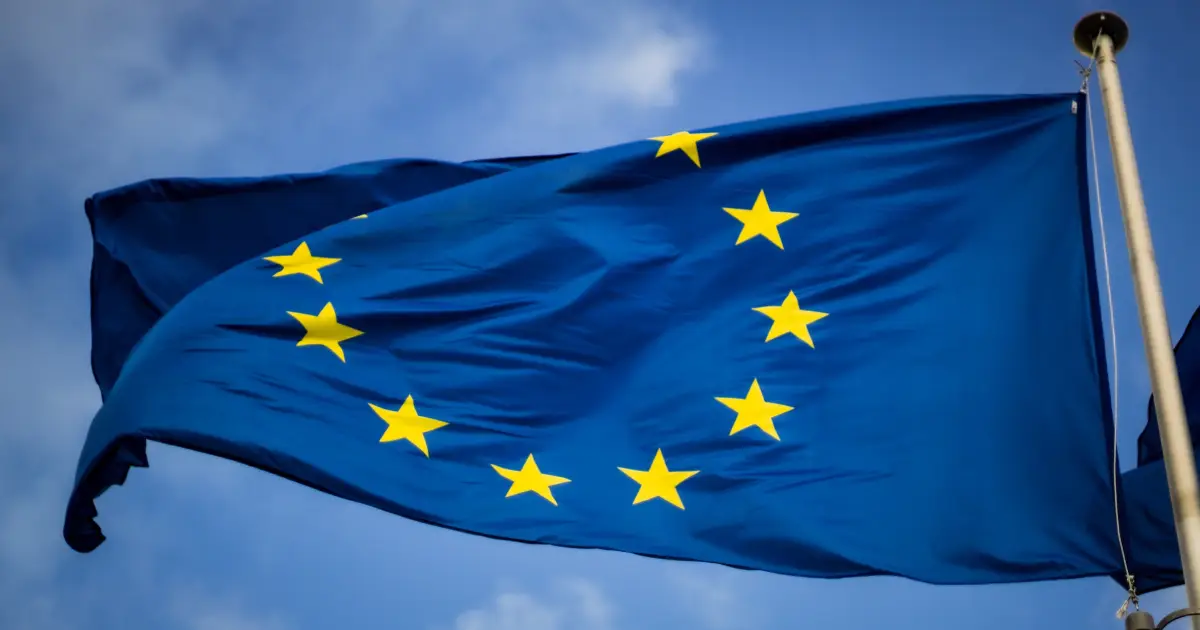 Bandeira da União Europeia azul com um círculo formado por estrelas amarelas hasteada e tremulando sobre um céu azul - ETIAS