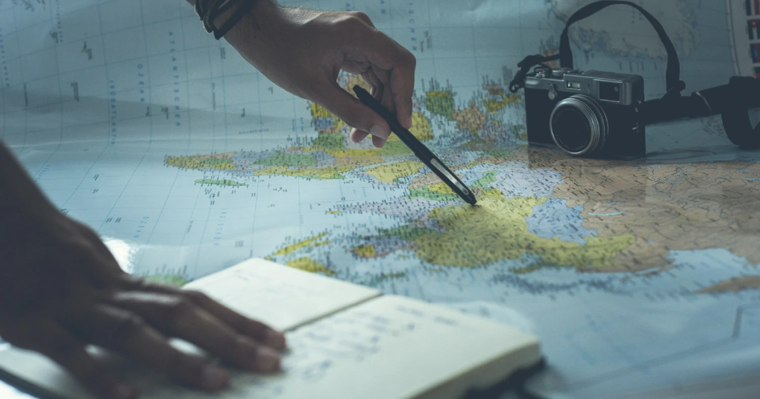 Pessoa escrevendo com um lápis em um mapa mundial