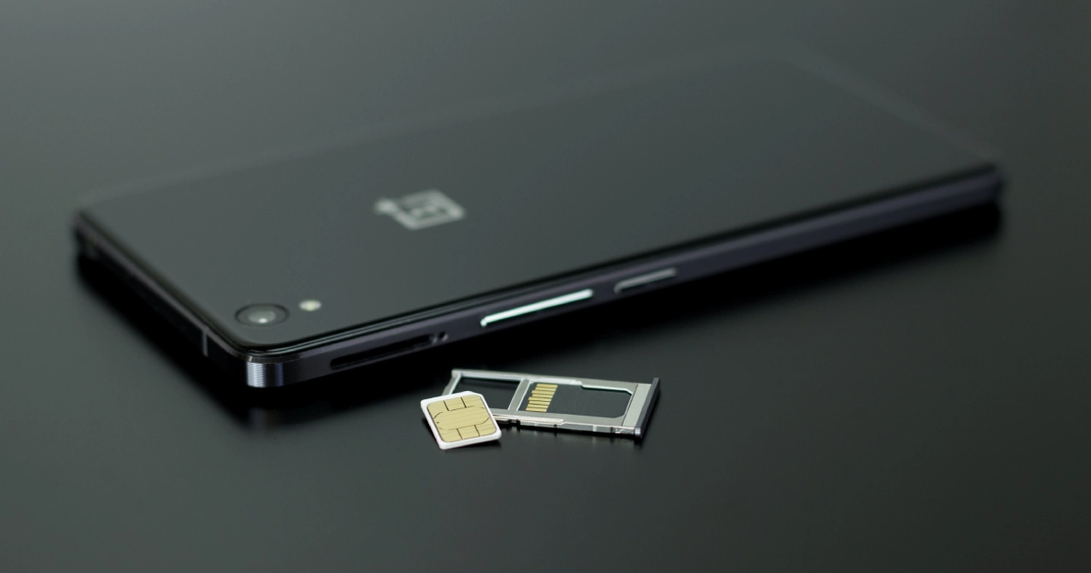 smartphone preto em cima de mesa preta com o sim card aparente