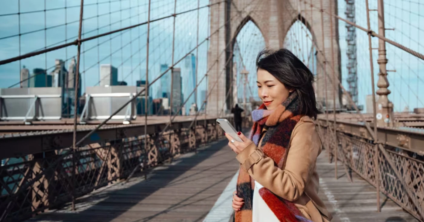 Mulher usando celular em uma ponte
