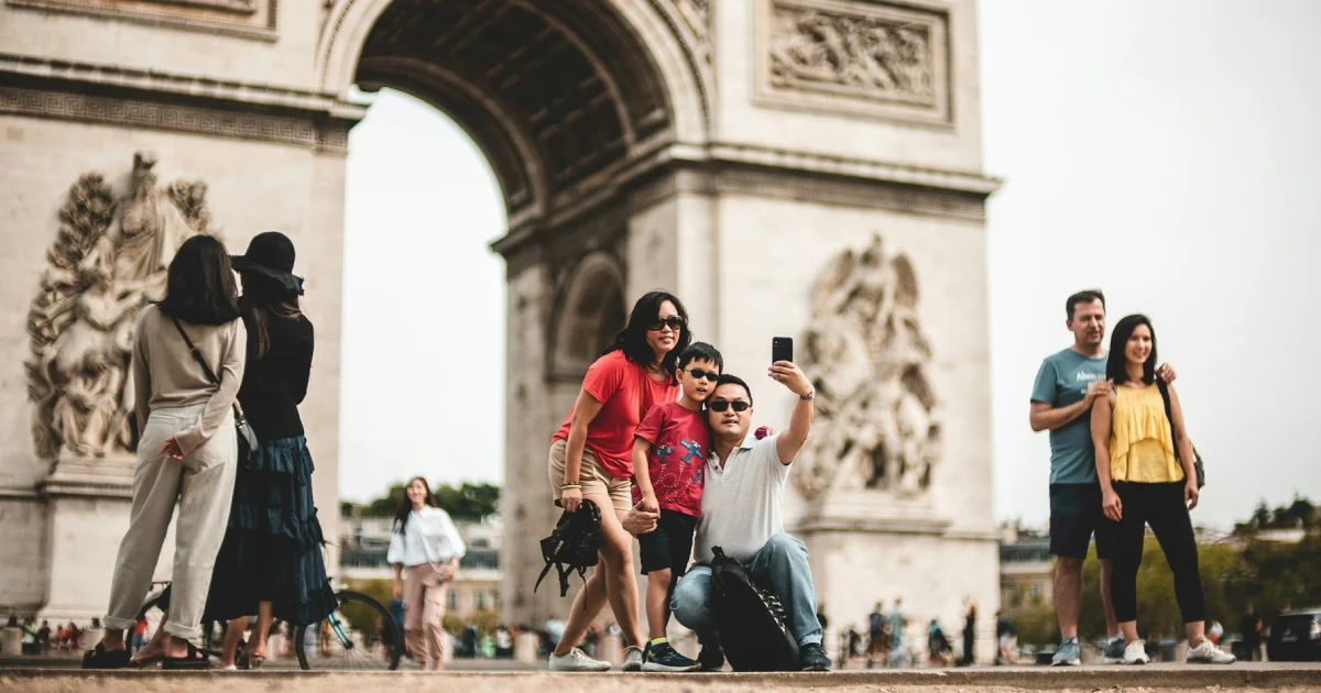 Turistas tirando foto na frente do Arco do Triunfo, em Paris